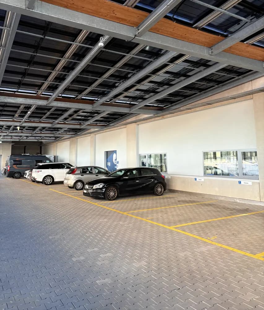 Gedecktes Parkdeck mit markierten Feldern und wenigen parkierten Autos