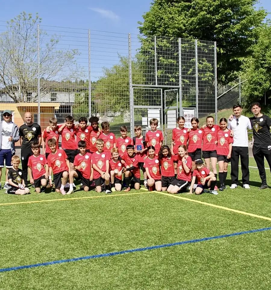 Das ganze Camp auf dem Rasen: Kinder in Rot, dahinter Trainer und Gäste