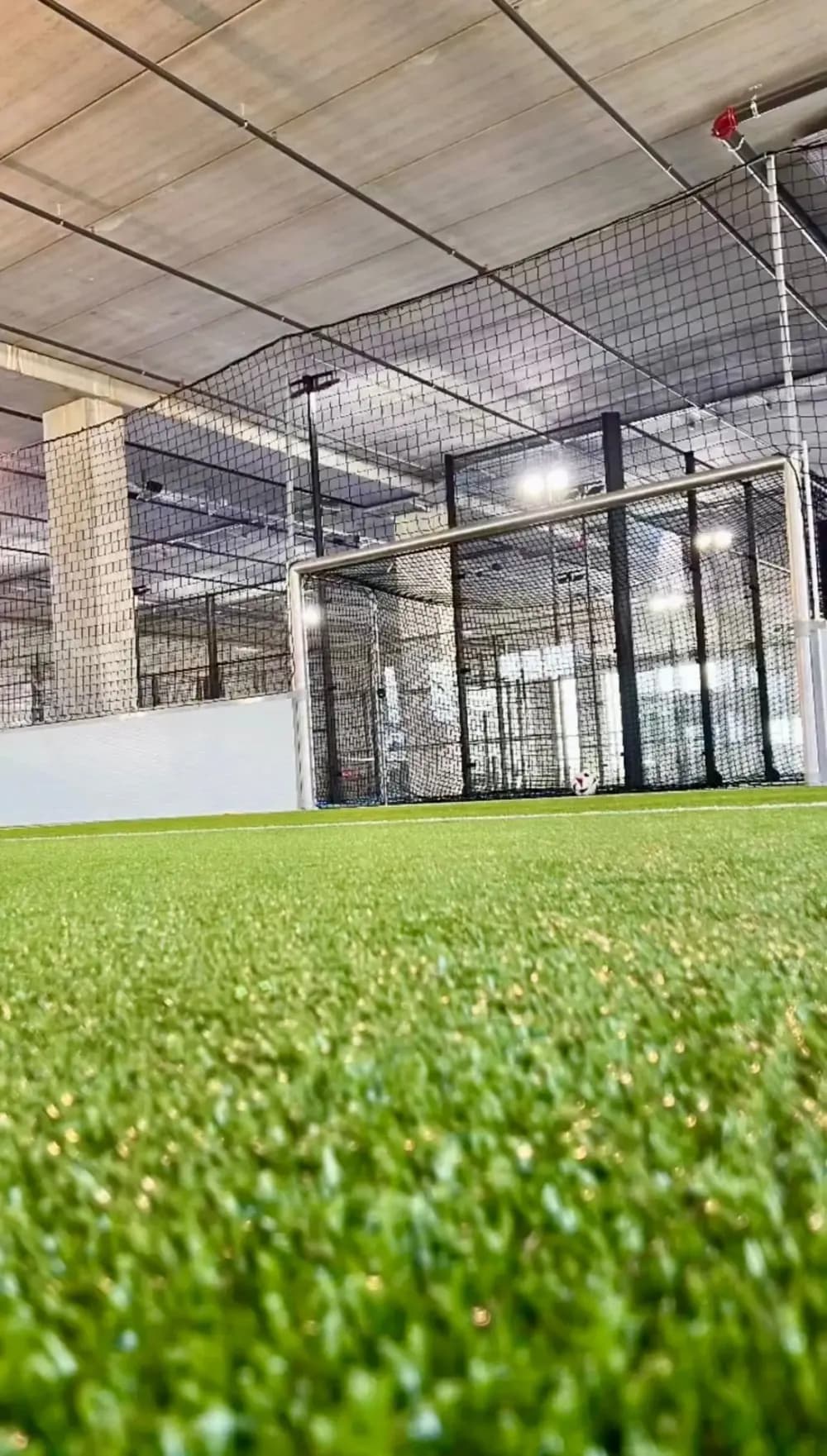 Tor mit Ball auf dem Kunstrasen der Indoor-Kunstrasenhalle Bubikon, dahinter das Fangnetz