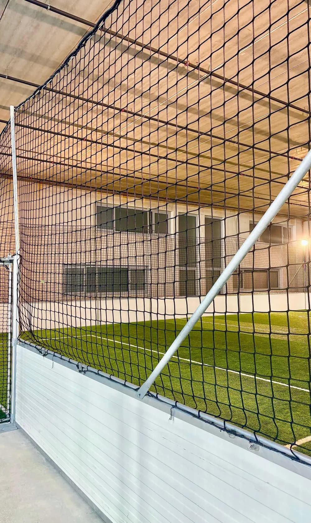 Blick durch das Fangnetz auf den Kunstrasen der Indoor-Kunstrasenhalle Bubikon