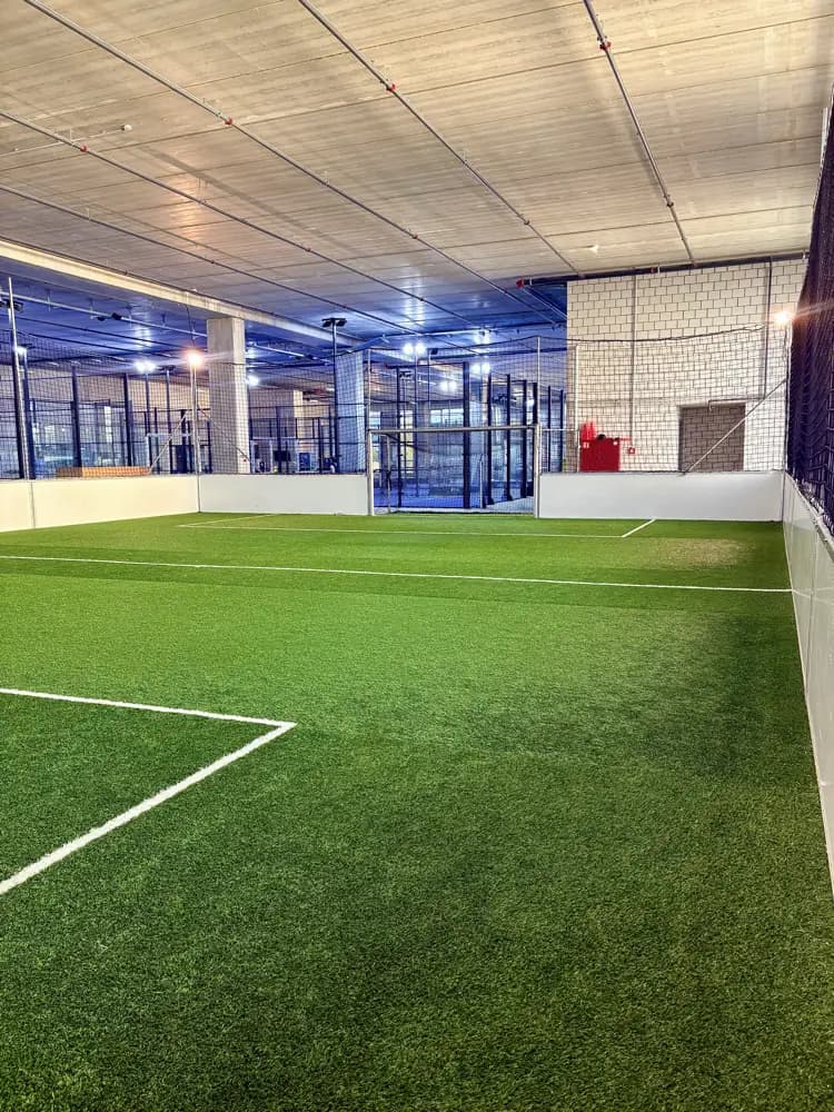 Die ganze Bahn der Indoor-Kunstrasenhalle Bubikon am Abend, mit Bande, Fangnetz und Flutlicht