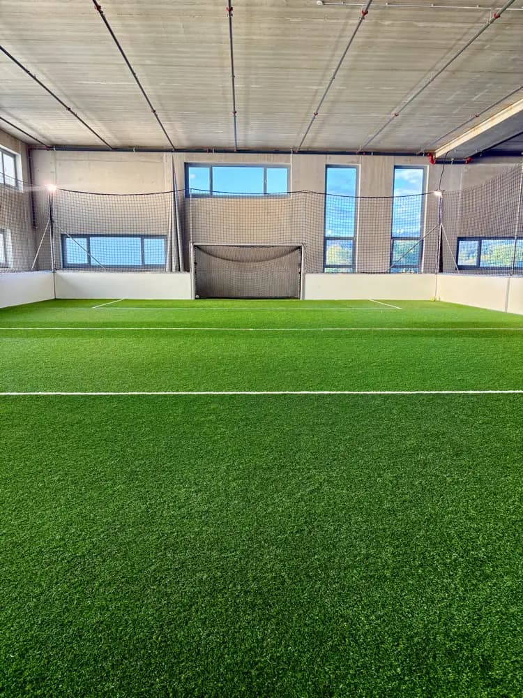 Der Kunstrasen der Indoor-Kunstrasenhalle Bubikon von der Mittellinie aus, dahinter das Tor vor dem Fangnetz